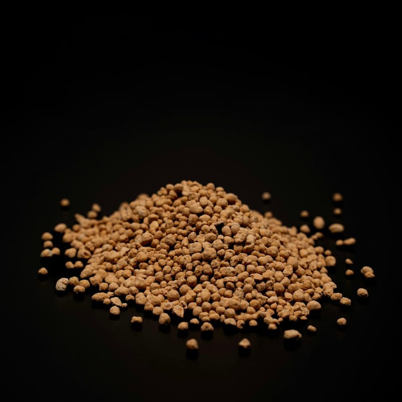 A loose pile of tan granular phosphate fertilizer