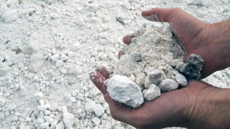 A hand holding pale chalky gypsum rock
