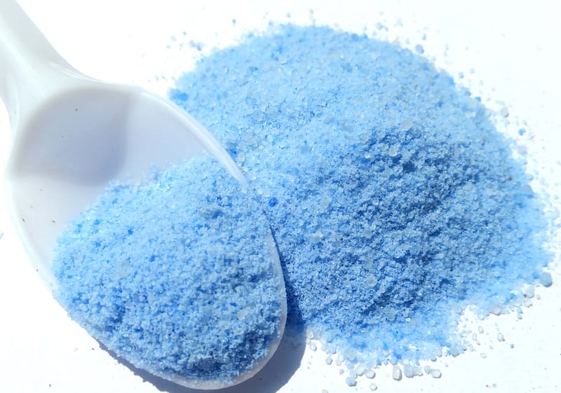 Pale blue water-soluble NPK powder on a scoop